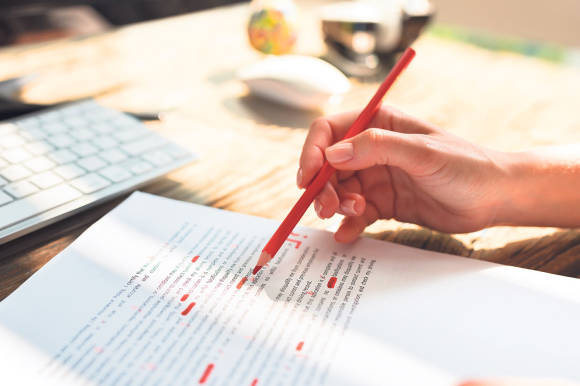 Eine Lektorin mit Rotstift bei der Arbeit Eine Lektorin mit Rotstift bei der Arbeit